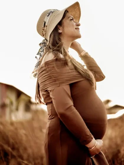 A hopeful portrait of the mom-to-be looking up towards the sun, her face lit by the warm golden light.