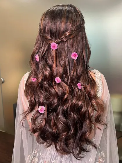 A detailed shot of Aayushi's romantic hairstyle, with soft waves and delicate pink flowers tucked in.