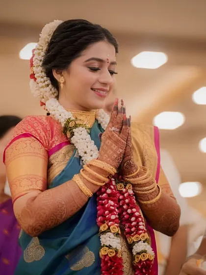 The bride, with hands joined in prayer, looks serene and beautiful during a wedding ritual.