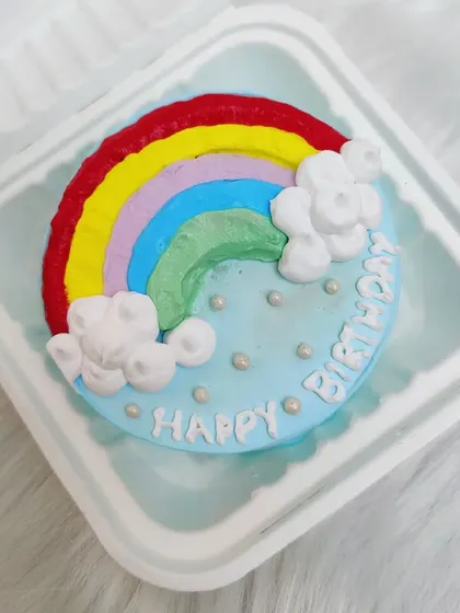 A cute and simple rainbow bento cake with buttercream clouds.
