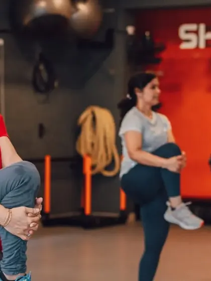 A candid shot of members during a warm-up, performing knee-to-chest stretches. We focus on preparing the body correctly for every workout.