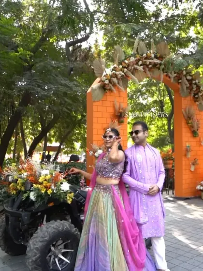 The happy couple posing for a photo by the decorated ATV and floral arch.