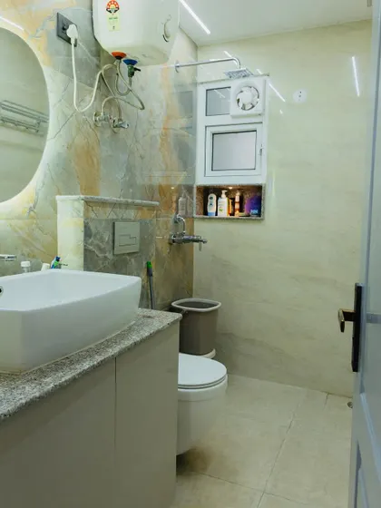 A full view of a well-designed bathroom. The space includes a vanity with storage, a wall-mounted toilet, and a niche in the shower area, all tied together with beautiful, earthy-toned tiles.