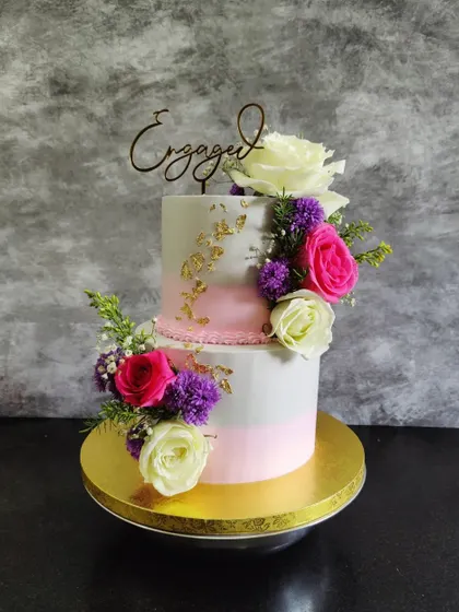 This two-tier engagement cake combines a soft pink watercolor effect with an array of fresh, colorful roses for a romantic and celebratory look.