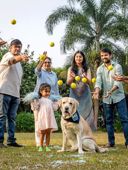 A fun family photo with Spike the Labrador, with everyone throwing tennis balls in the air. It's a creative and playful way to capture a family's energy.