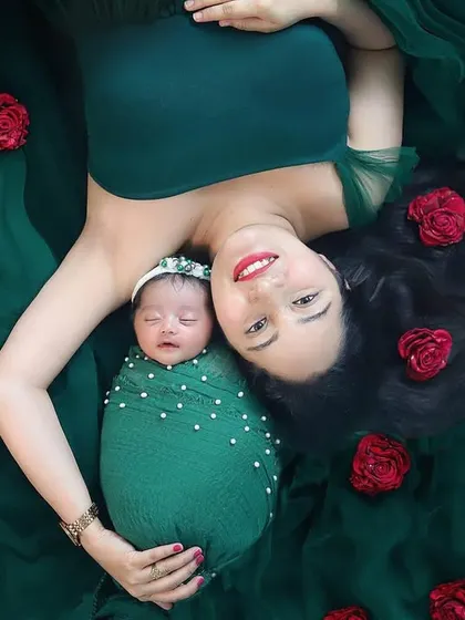 Picture perfect from above. This overhead shot of a mother and her newborn, surrounded by red roses on a bed of green, is like a beautiful painting. A stunning newborn photography concept.