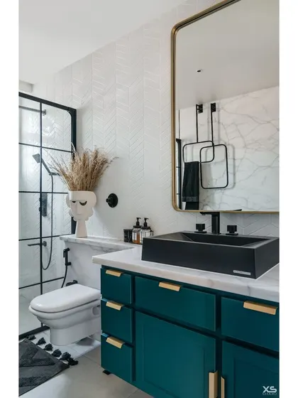 In another bathroom, we used a bold teal vanity with gold hardware, set against a white herringbone tile wall. A black vessel sink and matching fixtures add a contemporary edge.