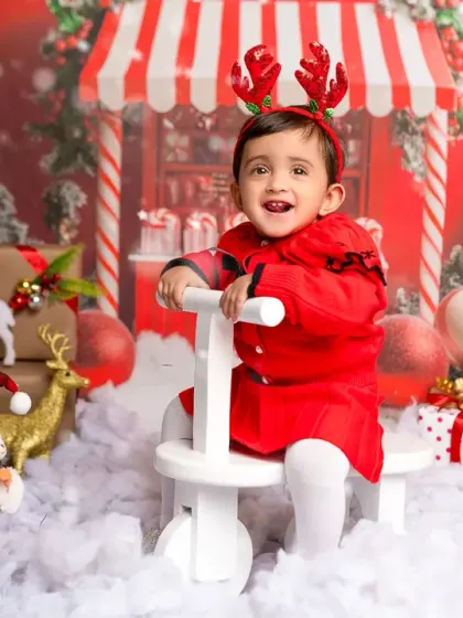 A joyful smile from a toddler enjoying our Christmas-themed photoshoot, complete with a toy reindeer and snowy props. Holiday mini-sessions are a great tradition.