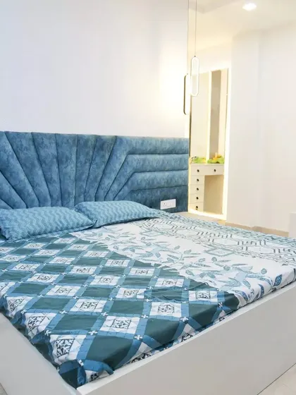 This bedroom showcases a vibrant blue upholstered headboard with a unique geometric design, adding a pop of color and personality to the space.