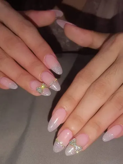 A beautiful and elegant set with a glittery silver French tip and a 3D bow made of sparkling rhinestones.