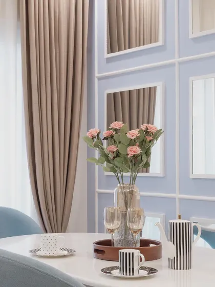 A close-up of the dining table setting, featuring striped monochrome tableware that provides a graphic contrast to the soft blue and beige tones of the room.