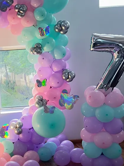 Yeh butterfly theme decoration ka close-up shot hai. Isme aap pastel color ke balloons aur silver butterflies ko saaf dekh sakte hain.