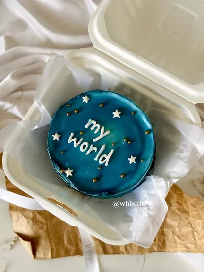 A "my world" bento cake with a deep blue galaxy-like glaze and tiny stars. These mini cakes are perfect for intimate celebrations or as a sweet personal treat.