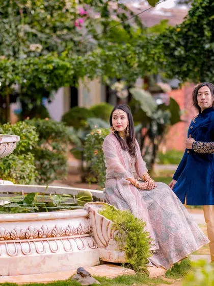 A serene and elegant portrait by a fountain. The couple's traditional outfits and the peaceful garden setting create a very timeless and beautiful image.