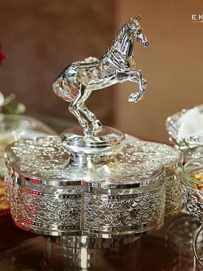 This silver dry fruit serving tray, adorned with an elegant horse motif, adds a touch of grandeur to any wedding or festive occasion. It is a statement piece that speaks of power and celebration.