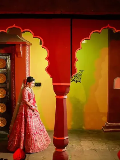 A bride stands within colorful, arched corridors, creating a royal and vibrant setting. This shot captures the grandeur of the venue and the elegance of the bride in her pink lehenga.