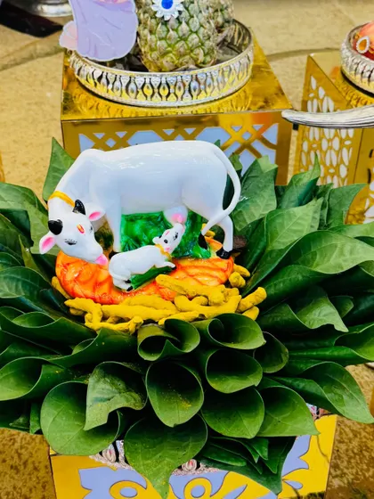 A unique platter featuring a cow and calf figurine, surrounded by an arrangement of fresh betel leaves.