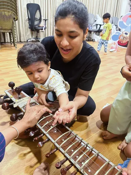 A parent helps their child explore the strings of a sitar. These shared moments of discovery are at the heart of our parent-toddler program.
