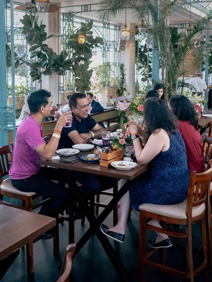 A group engaged in lively conversation over dinner. My long tables are perfect for fostering a communal dining experience, whether for a corporate team or a family celebration.