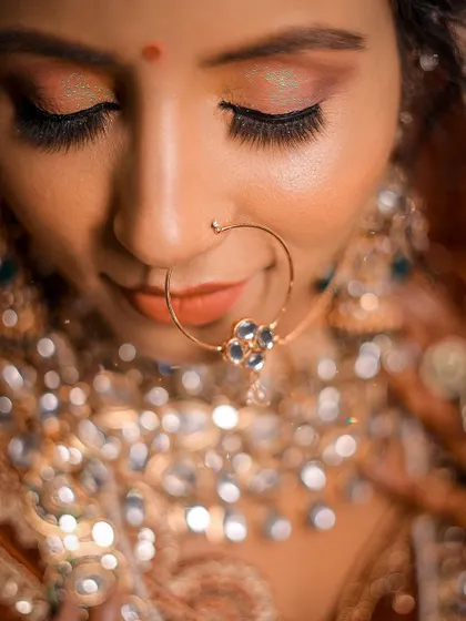 A tight close-up on the bride's face, showing the detail of her makeup and nath. The shallow depth of field creates a beautiful, soft look.