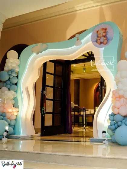 A grand, wave-shaped entrance arch for a teddy bear-themed party, decorated with blue and pink balloons.