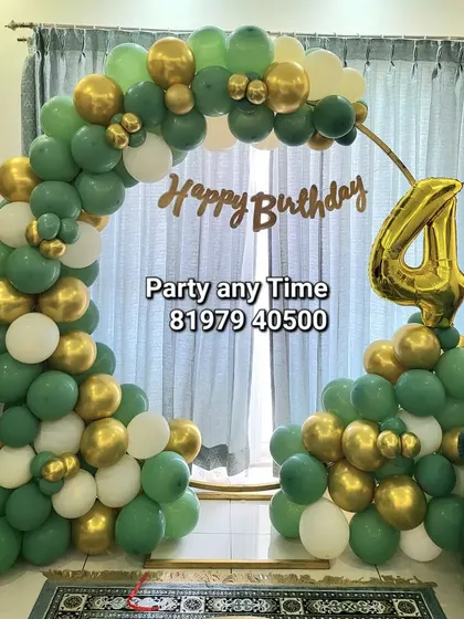 A simple and elegant balloon arch in green, white, and gold for a 4th birthday celebration at home.
