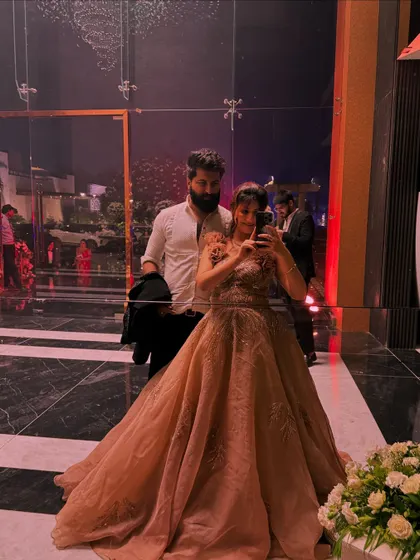 A mirror selfie of a couple, with her in a beautiful rental gown. This shows how my outfits are perfect for creating those picture-perfect memories at any event.