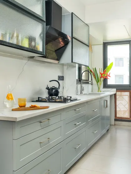 The kitchen combines different textures, with fluted glass overhead cabinets and sleek modern appliances.