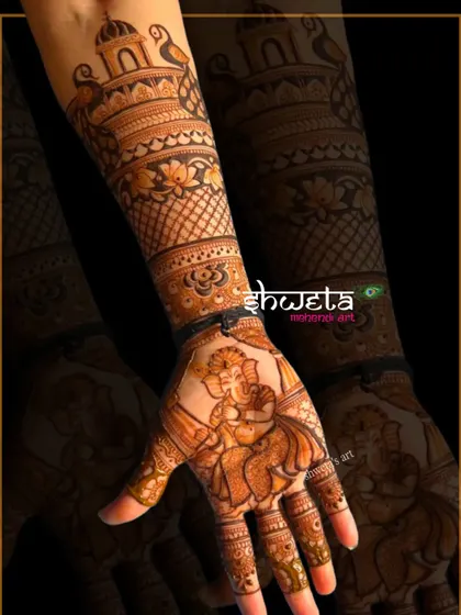A single hand adorned with a beautiful portrait of Lord Ganesha playing the flute. The surrounding arm design features traditional temple and floral patterns.
