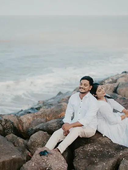 A serene moment as a couple relaxes on the rocks, looking out at the ocean.