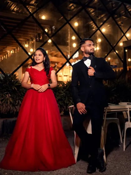 A stylish couple pose against a modern backdrop. The bride's classic red ball gown and the groom's sharp tuxedo create a chic and timeless look.