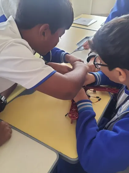 Students at Euro International School huddle together, working collaboratively to assemble a floor-cleaning robot during our workshop.