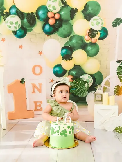 A lovely green-themed first birthday setup, complete with a beautiful cake. This photo captures the moment just before the fun of the cake smash begins.