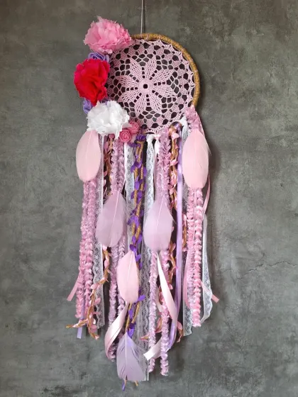 We love playing with color. This pink and red floral dreamcatcher uses bold pom-poms and soft feathers to create a vibrant and unique piece of boho home decor.