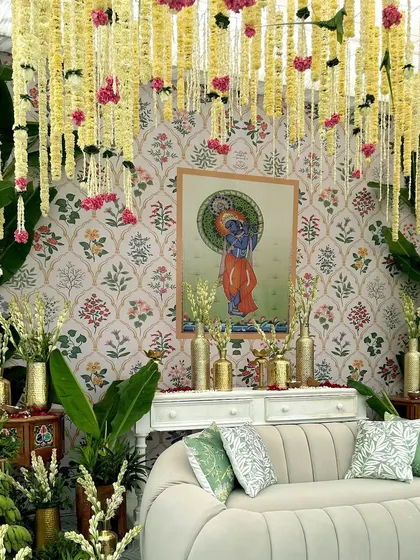 The central seating area for our South Indian themed Haldi, set against a backdrop of Pichwai art and framed by lush greenery and hanging floral strings.