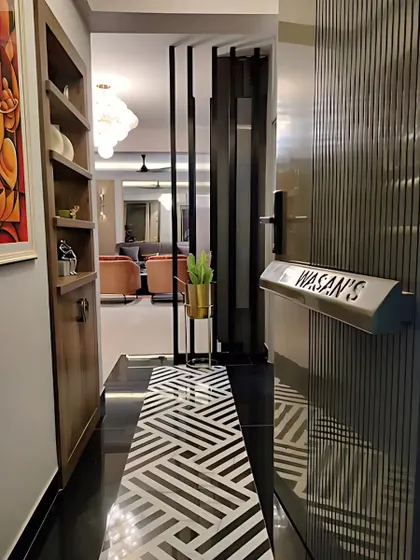 This condo entrance makes a statement with its bold black-and-white mosaic tile flooring and a custom nameplate. The view extends into the living room, creating a sense of open, flowing space.