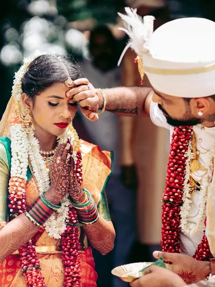 The groom applies the 'sindoor' to the bride's forehead, a key moment signifying their marriage. We work with photographers to ensure these critical shots are perfectly framed.