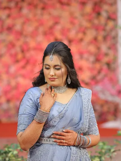 A solo portrait of the bride in her reception attire. The soft, romantic makeup and hairstyle perfectly complement the delicate embroidery of her outfit. This look is the epitome of modern bridal elegance.