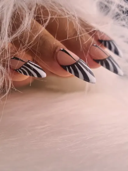 A bold and graphic design featuring sharp, stiletto nails with a modern take on zebra print. The negative space and clean lines give this classic pattern a contemporary and edgy feel.