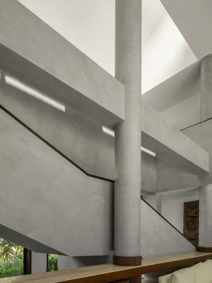 The central sculptural staircase, rendered in monolithic concrete. It is not merely for circulation but acts as a vertical sculpture connecting the different levels of the home and gallery.