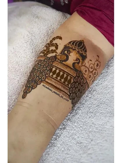 The beginning of a leg design, with two peacocks framing a central architectural element.