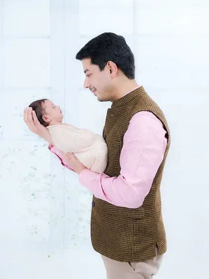 A father holds his tiny newborn in his hands, looking down with love and awe. This shot beautifully captures the scale and preciousness of a new life.