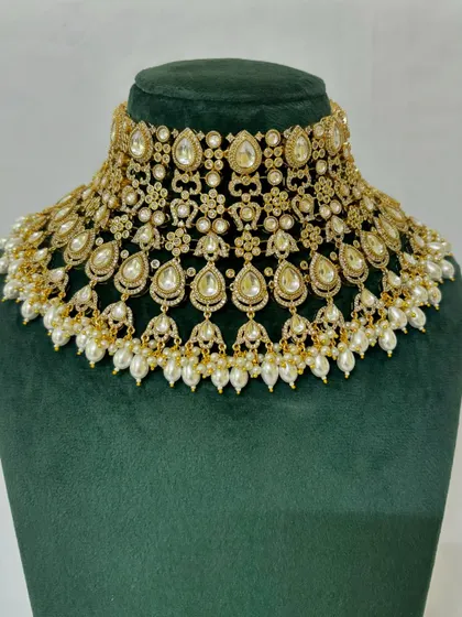 A wide choker necklace made with Kundan stones and pearl drops, perfect for a grand bridal look. This piece is available for rent.