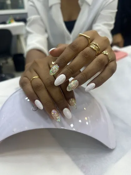 A classic and clean look with a touch of sparkle. This set features crisp white polish on almond-shaped nails, with accent nails adorned with iridescent glitter for a simple yet glamorous effect.