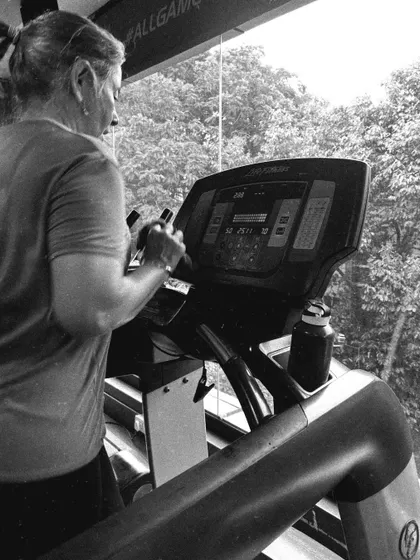 A client focuses on her stats while on the treadmill, tracking her progress and pushing her limits.