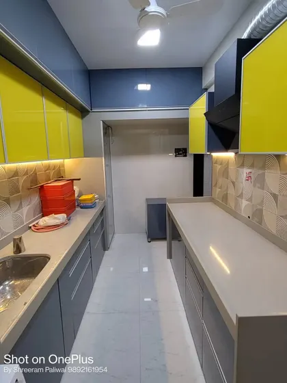 For the Savla's kitchen in Kandivali, I used a vibrant color combination of lemon yellow and cool grey. The high-gloss finish and patterned backsplash create a cheerful and energetic atmosphere.