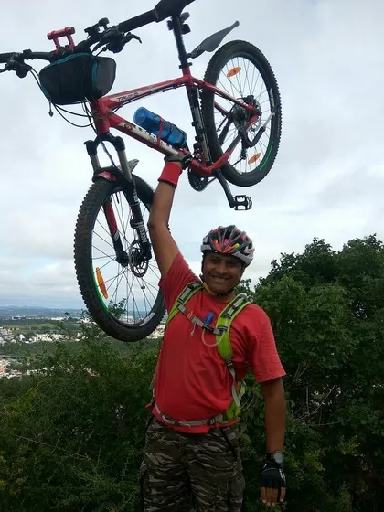 Another triumphant rider hoisting his red mountain bike, with the city visible in the distance.