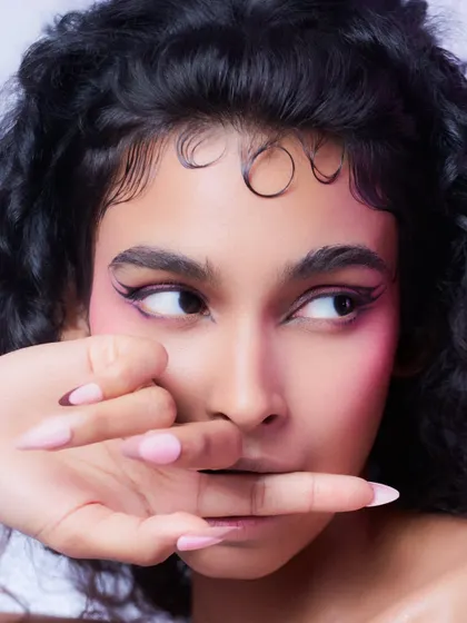 A close-up focusing on the eyes and the detailed hair styling. The clean lighting and simple background ensure that the intricate details of the makeup and hair are the main subject.