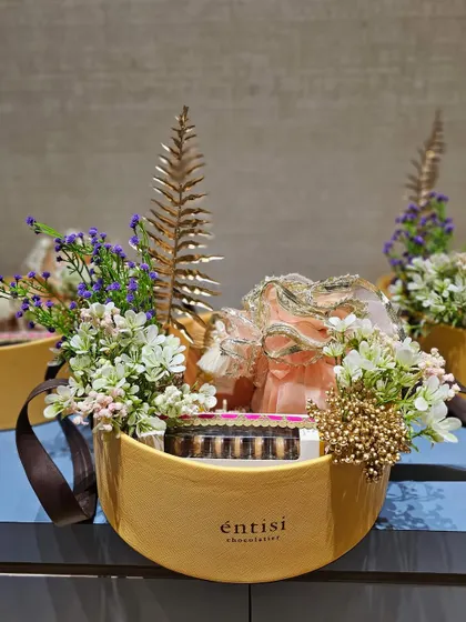 For Entisi Chocolatier, I curated these elegant oval hampers. The design combines their chocolate boxes with delicate floral arrangements, golden ferns, and organza potlis, creating a very pretty and high-end presentation.