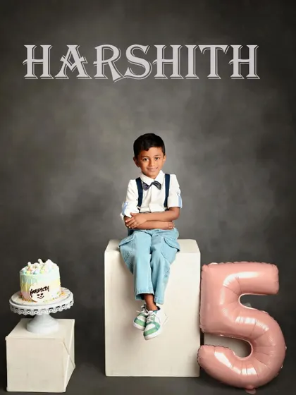 A classic birthday portrait for a five-year-old. The simple studio setup with the cake and balloon keeps the focus on the proud birthday boy.
